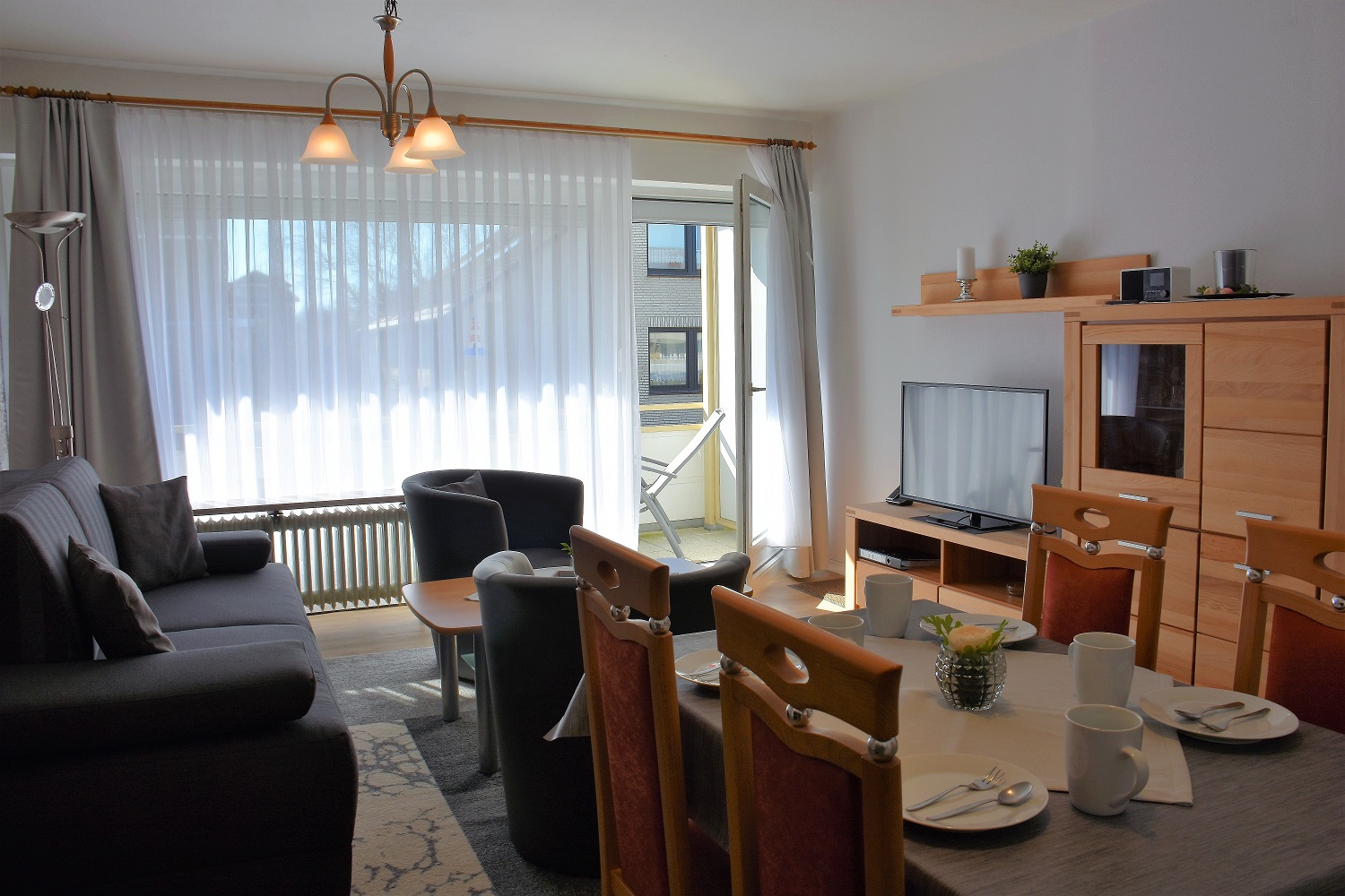 Wohnzimmer mit Couch, TV und Esstisch in der Ferienwohnung im Haus „Vier Jahreszeiten“